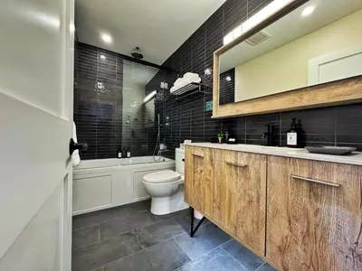 a bathroom with a toilet and a tub and a sink at Artisan Suites on Bowen in Bowen Island