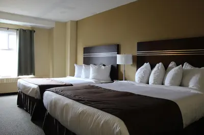two beds in a hotel room with white pillows at Walking Eagle Inn & Lodge in Rocky Mountain House