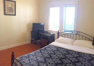 a bedroom with a bed and a desk with a television at Imperial House in Burnaby