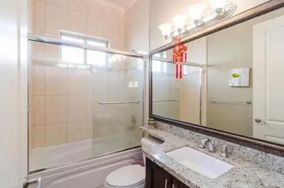 a bathroom with a sink and a toilet and a mirror at Imperial House in Burnaby