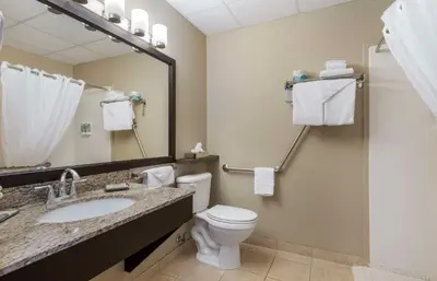a bathroom with a toilet and a sink and a mirror at Best Western Rocky Mountain House Inn & Suites in Rocky Mountain House