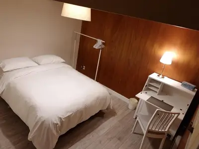 a bedroom with a bed and a desk with a lamp at City Gardens Suites B&B in North Vancouver