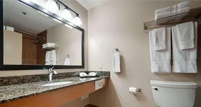 a bathroom with a sink and a mirror and a toilet at Best Western Plus Chateau Inn Sylvan Lake in Sylvan Lake