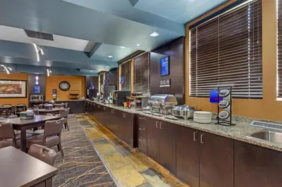 a restaurant with wooden cabinets and tables and chairs at Best Western Bonnyville Inn & Suites in Bonnyville