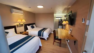 a hotel room with two beds and a desk at Harbour Light Motel in Nanaimo