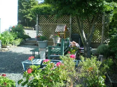 a garden with two green chairs and flowers at Island View B&B in Nanaimo