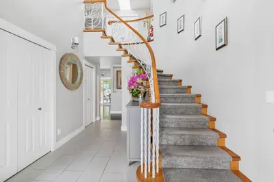 a staircase in a home with white walls and wooden railings at Casa Grande Lakeview House in West Kelowna
