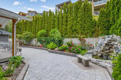 a patio with flowers and a stone wall at Casa Grande Lakeview House in West Kelowna