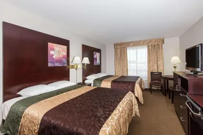 a hotel room with two beds and a flat screen tv at Super 8 by Wyndham Innisfail in Innisfail