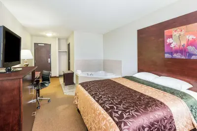 a hotel room with a bed and a desk and a television at Super 8 by Wyndham Innisfail in Innisfail