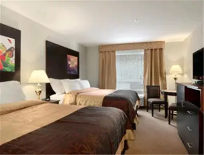 a hotel room with two beds and a desk at Super 8 by Wyndham Innisfail in Innisfail