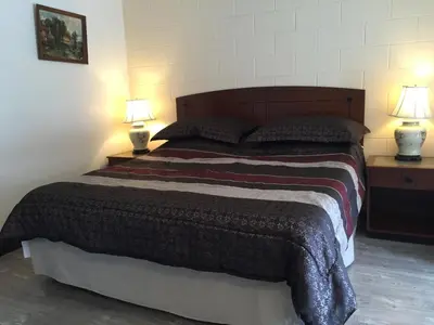 a bedroom with a large bed with two lamps at City Centre Motel older building in Hope