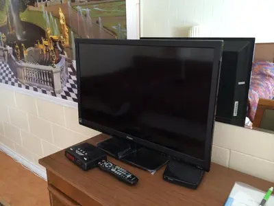 a flat screen tv sitting on a table with two remote controls at City Centre Motel older building in Hope