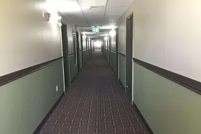 a hallway with a long corridor with green walls at Super 8 by Wyndham Hardisty in Hardisty