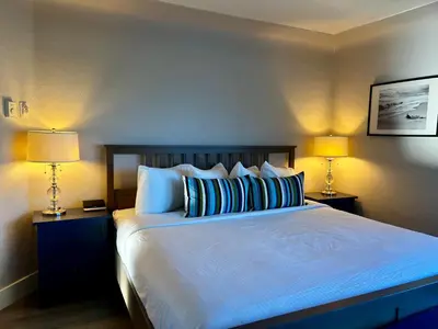 a bedroom with a large bed with blue sheets and two lamps at Buccaneer Inn in Nanaimo