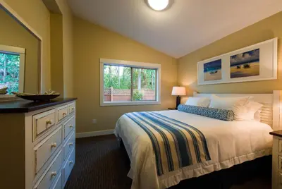 a bedroom with a bed and two windows at Oceanside Village Resort in Parksville