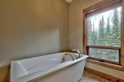 a white bath tub in a bathroom with a window at 17 Village Walk Sun Peaks BC in Sun Peaks