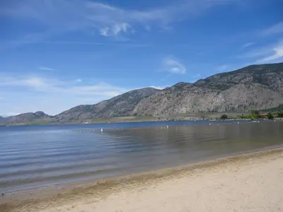 a view of a beach with mountains in the background at Falcon Resort in Osoyoos