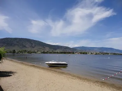 a boat sitting on the shore of a body of water at Falcon Resort in Osoyoos