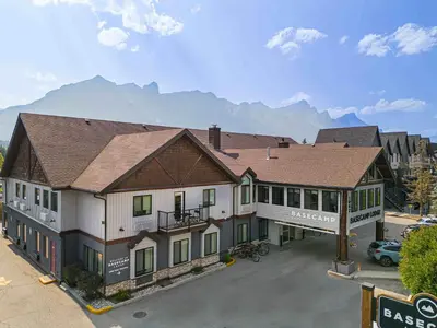 a large building with mountains in the background at Basecamp Lodge Canmore in Canmore