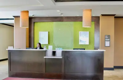 a woman sitting at a reception desk in a lobby at Hilton Garden Inn Edmonton International Airport in Leduc