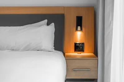 a bed with a white pillow and a night stand at West Coast Suites at UBC in Vancouver