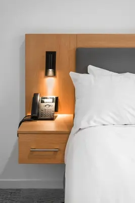 a phone on a night stand next to a bed at West Coast Suites at UBC in Vancouver
