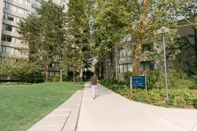 a man walking down a sidewalk in front of a building at West Coast Suites at UBC in Vancouver