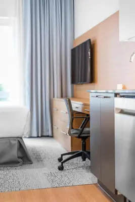 an office with a desk with a chair and a television at West Coast Suites at UBC in Vancouver