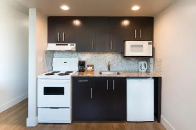 a kitchen with black cabinets and white appliances at Gage Suites at UBC in Vancouver