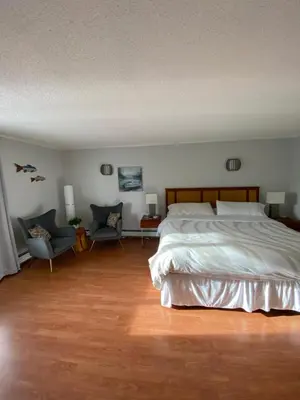 a bedroom with a large bed and two chairs at Rose Cottage Bed & Breakfast in Valemount