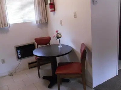 a small dining room table with two chairs and a vase with flowers at Canyon Alpine Motel in Boston Bar