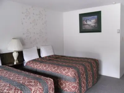 a hotel room with two beds and a lamp at Canyon Alpine Motel in Boston Bar