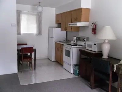 a small kitchen with a white refrigerator and a table at Canyon Alpine Motel in Boston Bar