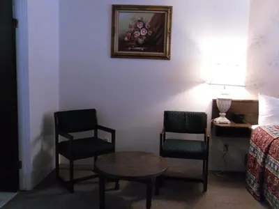 a room with two chairs and a table and a bed at Canyon Alpine Motel in Boston Bar