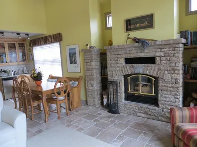 a living room with a stone fireplace and a table at Buffaloberry Bed & Breakfast in Banff