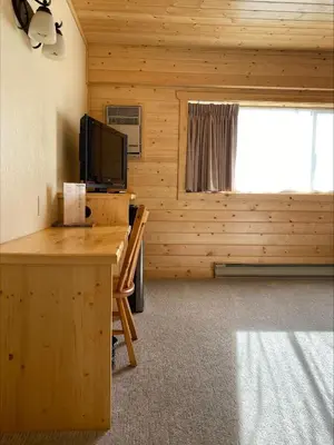 a room with a desk with a television and a window at Stork Nest Inn in Smithers