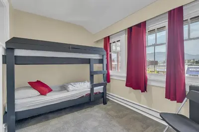 a bedroom with a bunk bed and two windows at HI Penticton - Hostel in Penticton