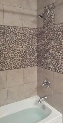 a bathroom with a bath tub with a stone wall at Riverbend Guest House in Chilliwack