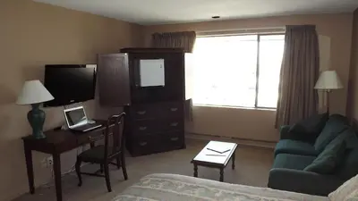 a living room with a couch and a desk with a television at The Pacific Inn in Prince Rupert