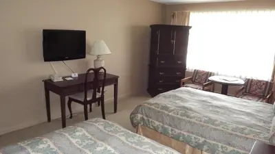 a hotel room with two beds and a desk and a television at The Pacific Inn in Prince Rupert