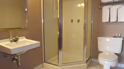 a bathroom with a shower and a sink and a toilet at The Pacific Inn in Prince Rupert