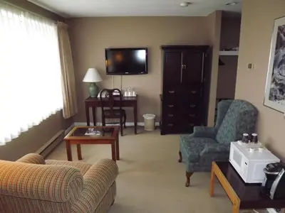 a living room with a couch and chairs and a tv at The Pacific Inn in Prince Rupert