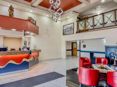 a lobby of a fast food restaurant with red chairs at Super 8 by Wyndham High River AB in High River