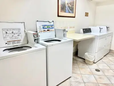 a laundry room with two washes and a counter at Super 8 by Wyndham High River AB in High River