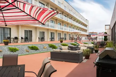 a hotel patio with chairs and tables and an umbrella at Days Inn by Wyndham Cranbrook Conference Centre in Cranbrook