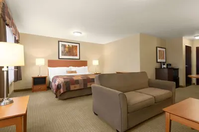 a hotel room with a bed and a couch at Ramada by Wyndham Drayton Valley in Drayton Valley