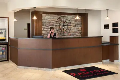 a woman talking on a cell phone at a hotel lobby at Ramada by Wyndham Drayton Valley in Drayton Valley