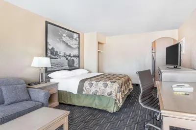 a small hotel room with a bed and a couch at Super 8 by Wyndham Stettler in Stettler