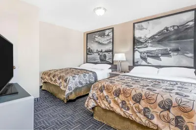 a hotel room with two beds and a flat screen tv at Super 8 by Wyndham Stettler in Stettler